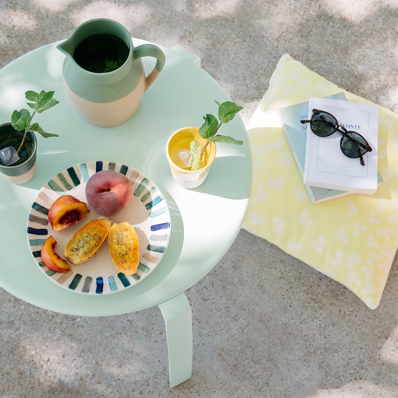 Light green table with a plate of food, cup, and sunglasses on a textured surface