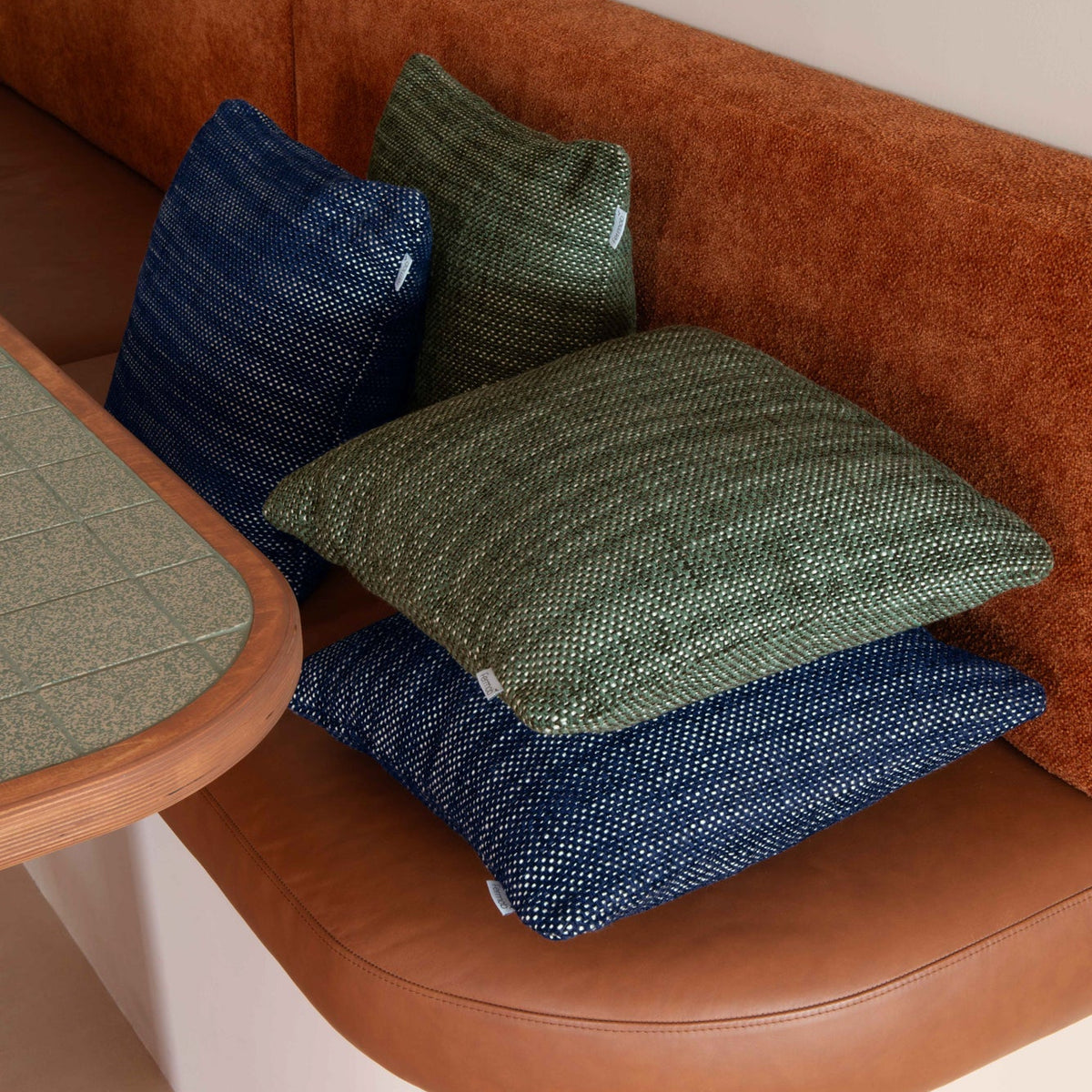 Green and blue textured cushions on a brown sofa