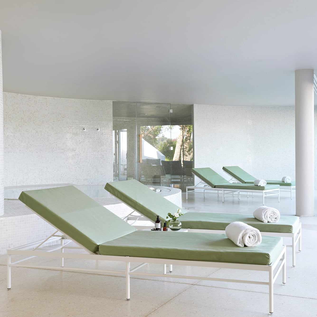 Modern indoor area with green lounge chairs and a white floor.