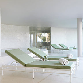 Modern indoor area with green lounge chairs and a white floor.