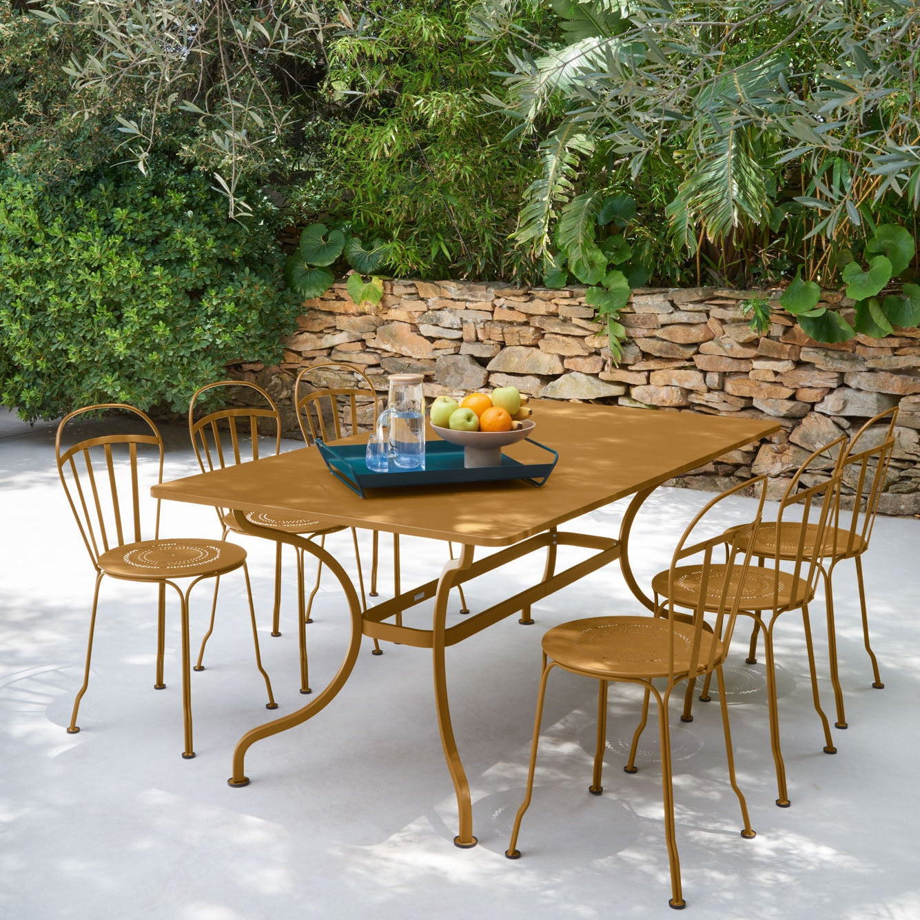 Outdoor dining set with a metal table and chairs in a garden setting.