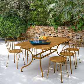 Outdoor dining set with a metal table and chairs in a garden setting.