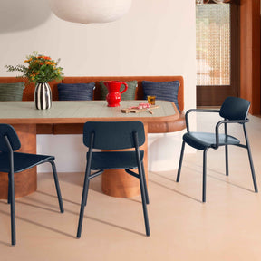 Modern dining area with blue chairs, a wooden table, and decorative items.