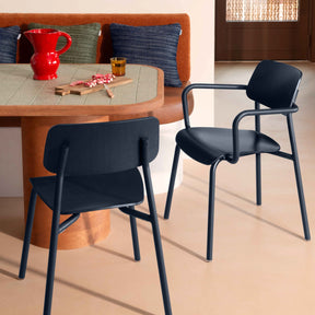 Two dark blue chairs in front of a wooden table with a red pitcher and other items.