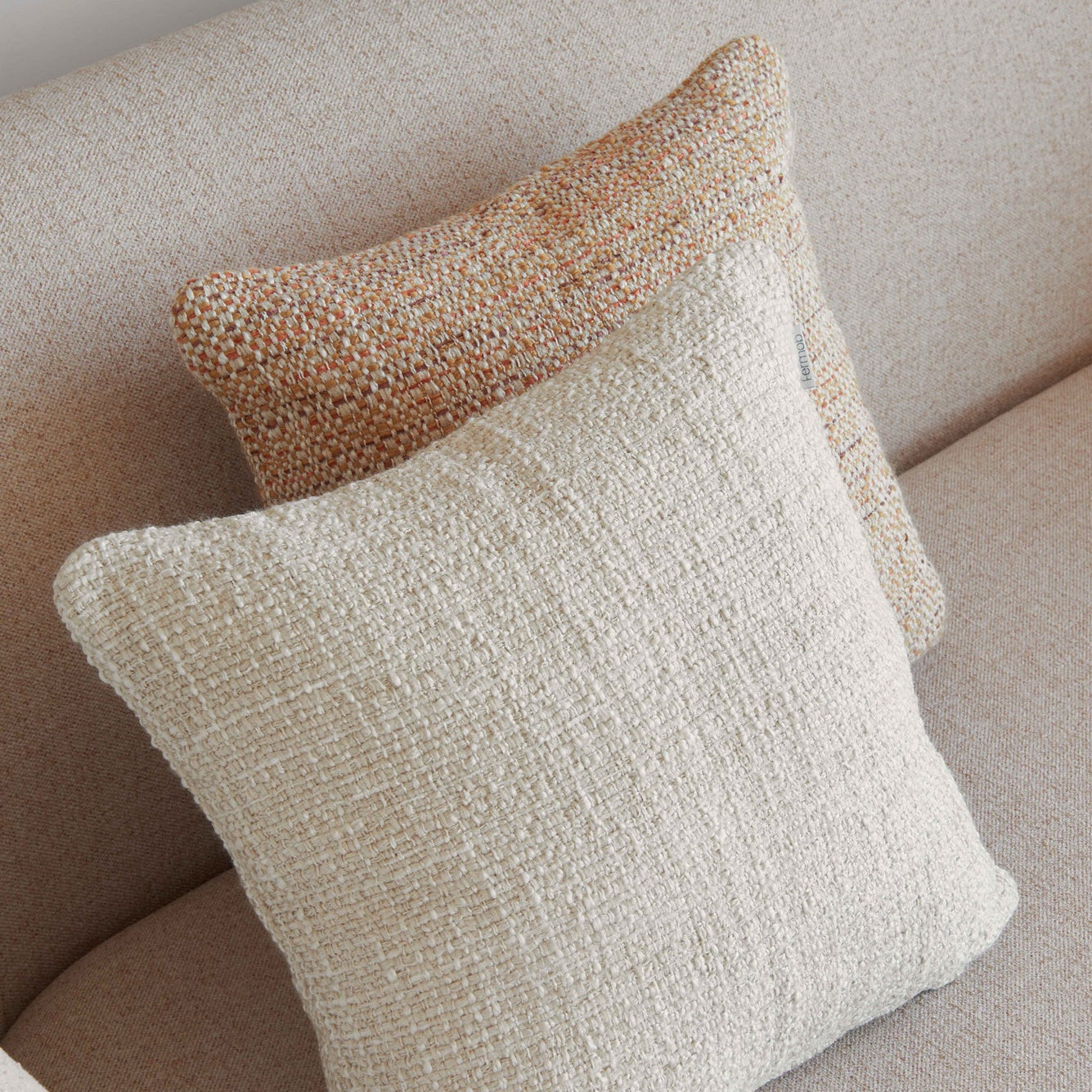 Two textured pillows on a beige sofa